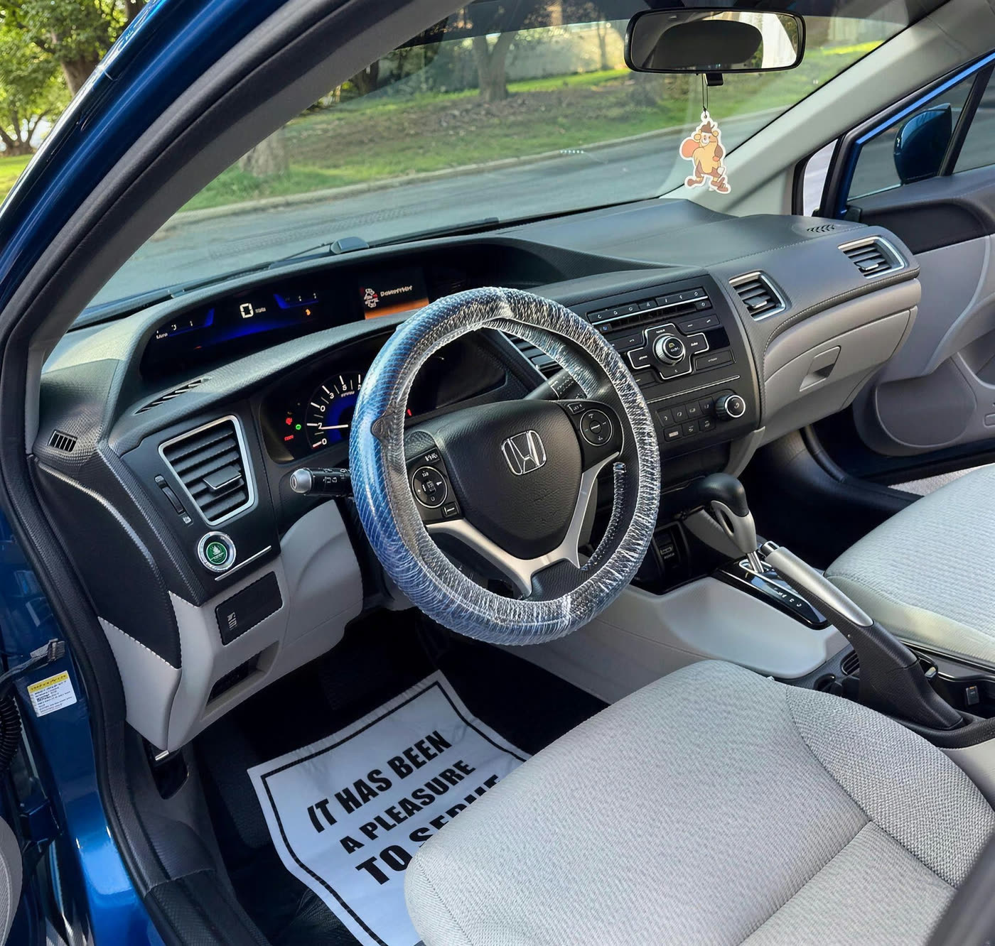 Blue Honda Civic interior after detailing with a protective steering wheel cover and Key City Details floor mat in place