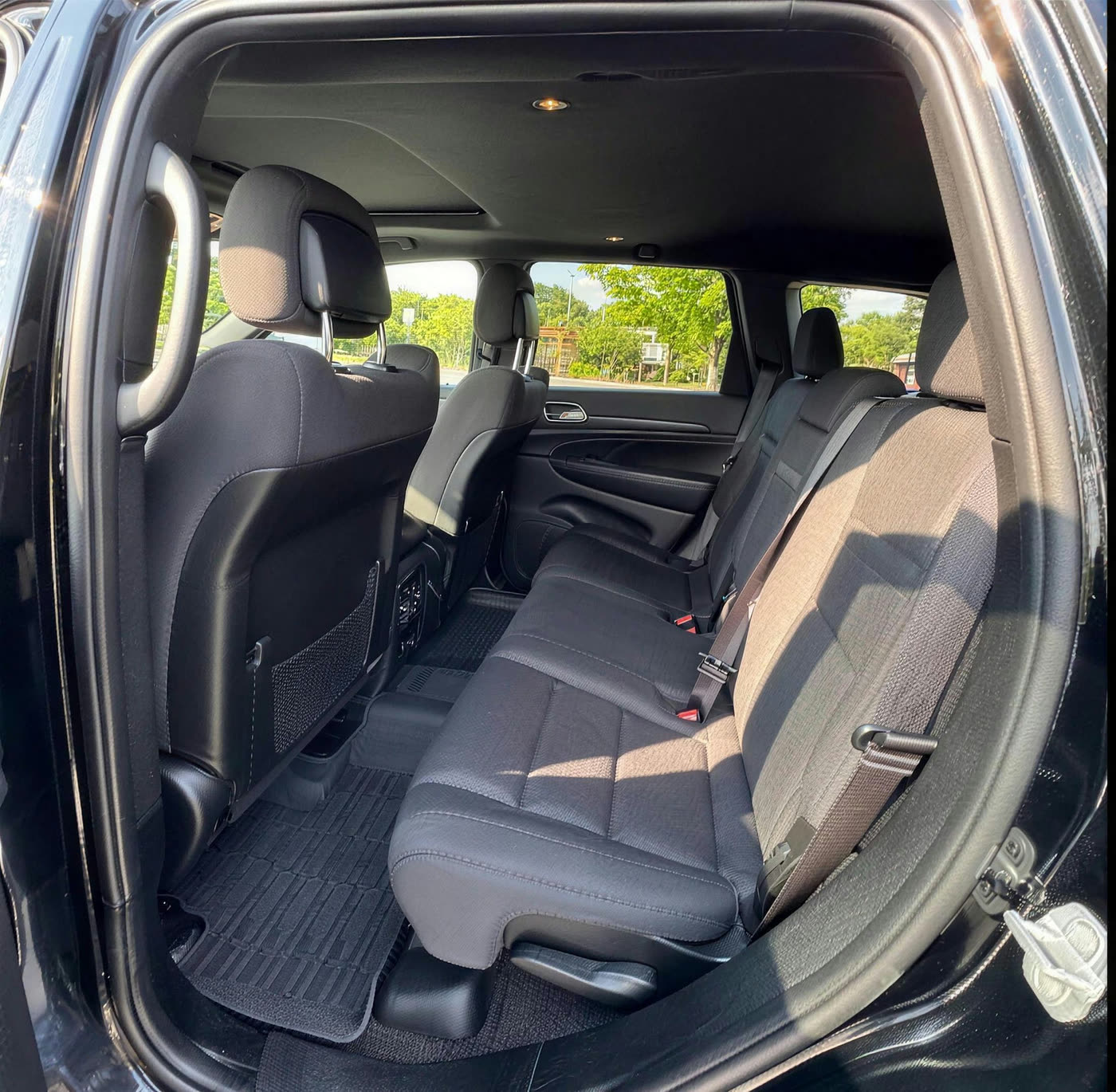 Second row of a Jeep Grand Cherokee after shampooing, with clean cloth seats and vacuumed rubber floor liners
